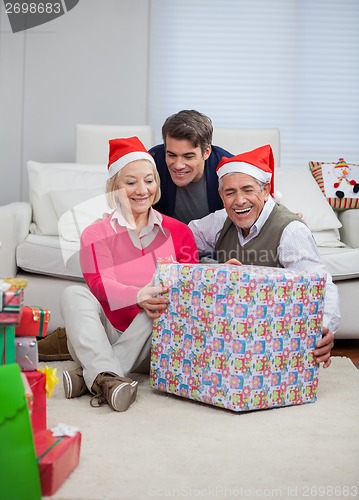 Image of Man With Parents Holding Christmas Present