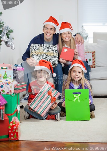 Image of Family In Santa Hats Holding Christmas Gifts