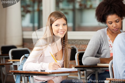 Image of Student Sitting At Desk With Classmates In Classroom