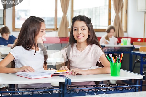 Image of Schoolgirl Sitting With Classmate Looking At Her