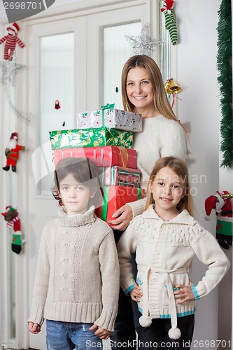 Image of Family With Gifts Standing By Door During Christmas