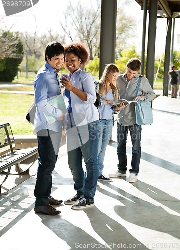 Image of Woman Showing Mobilephone To Classmate At University Campus