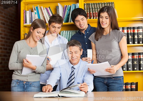 Image of University Teacher With Books Explaining Students In Library