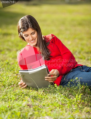 Image of Woman Reading Book While Relaxing On Grass At Campus