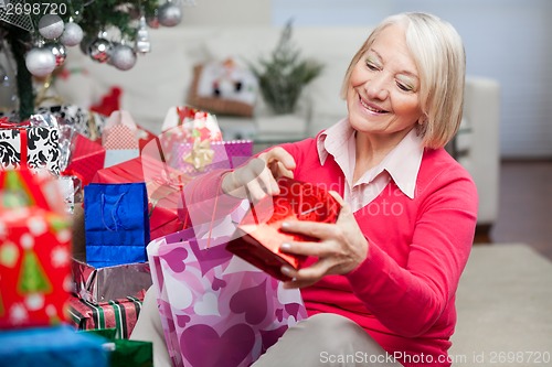 Image of Woman Looking In Bag While Sitting By Christmas Gifts
