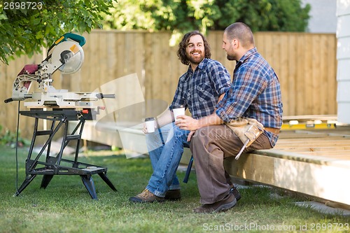 Image of Workers Holding Disposable Coffee Cups On Wooden Frame At Site