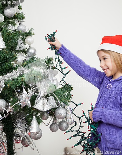 Image of Girl Decorating Christmas Tree With Fairy Lights