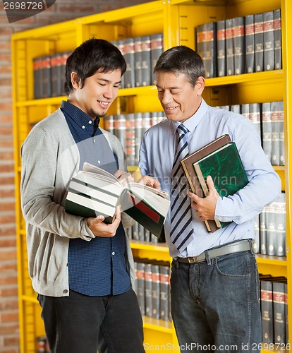 Image of Librarian Holding Books While Explaining Student In Library