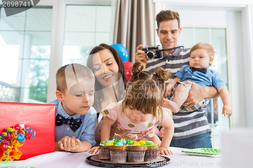 Image of Family Watching Girl Blowing Out Candles On Birthday Cake