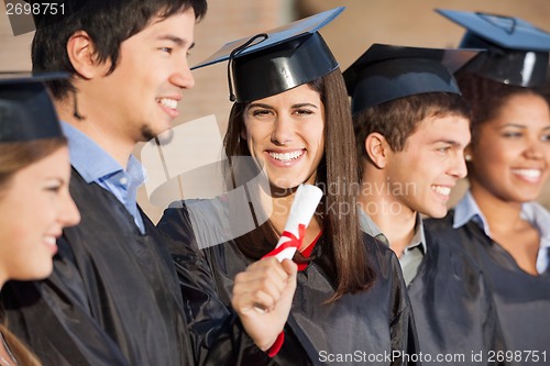 Image of Graduate Student Holding Diploma While Standing With Friends At