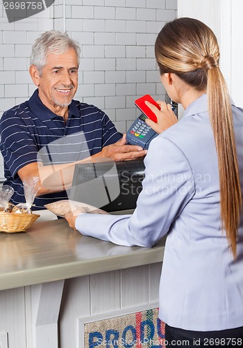 Image of Female Customer Paying Through Mobile Phone In Store