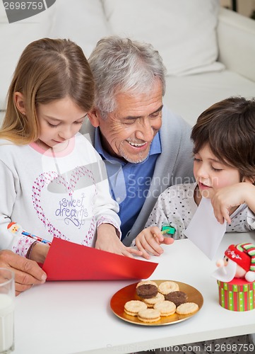 Image of Smiling Man Assisting Children In Making Greeting Card