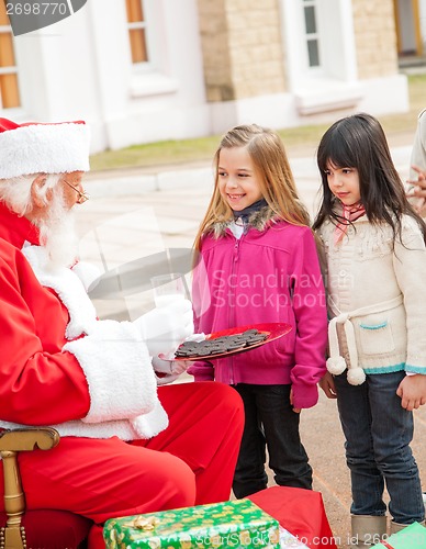 Image of Santa Claus With Biscuits And Milk Looking At Children