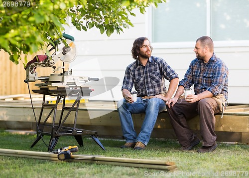 Image of Carpenters With Disposable Cups Looking At Each Other On Frame