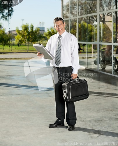 Image of Confident Teacher With Laptop Bag And Books Standing On College