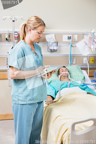 Image of Nurse Using Digital Tablet While Patient Resting On Bed