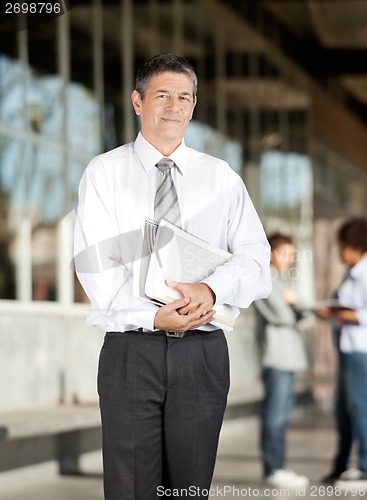 Image of Professor With Book Standing On University Campus