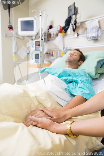 Image of Woman Holding Man's Hand Lying On Bed