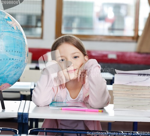 Image of Schoolgirl With Stack Of Books And Globe At Desk