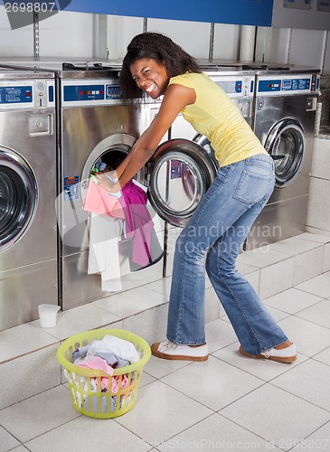 Image of Woman Pushing Clothes In Washing Machine