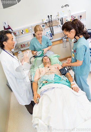 Image of Nurses And Doctor Examining Critical Male Patient