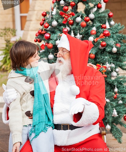 Image of Boy Looking At Santa Claus In Front Of Christmas Tree