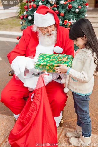 Image of Girl Receiving Present Against Christmas Tree