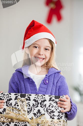 Image of Girl In Santa Hat Holding Christmas Gift