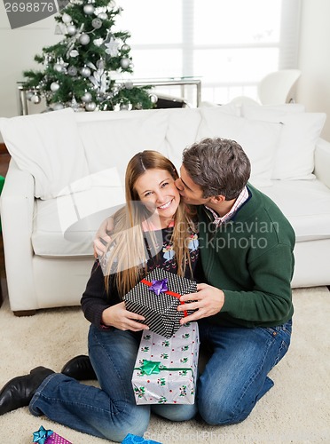 Image of Man With Christmas Gift Kissing Woman On Cheek