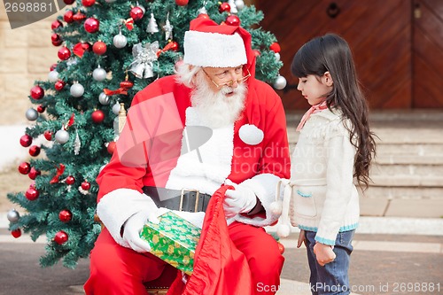 Image of Santa Claus Giving Gift To Girl