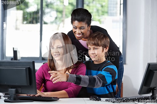 Image of Teacher Assisting Teenage Students In Computer Lab