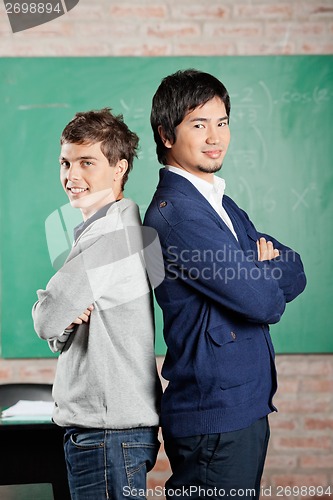 Image of Male Students Standing Hands Folded Against Greenboard In Classr