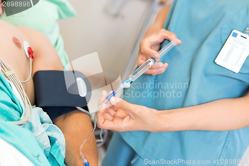 Image of Nurse Injecting Dosage In IV Tube Attached To Patient