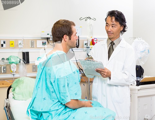 Image of Doctor With Clipboard Discussing Medical Report In Hospital