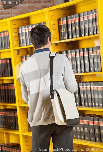 Image of Student Carrying Bag While Standing In College Library