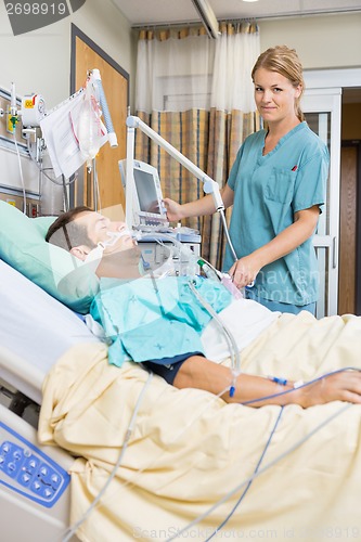 Image of Nurse Examining Young Patient Lying On Bed