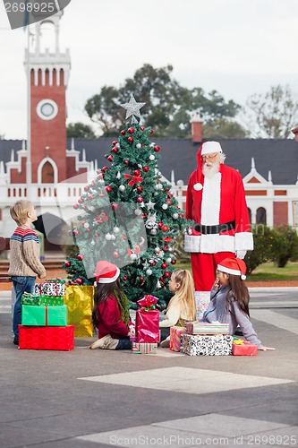 Image of Santa Claus And Children By Decorated Christmas Tree