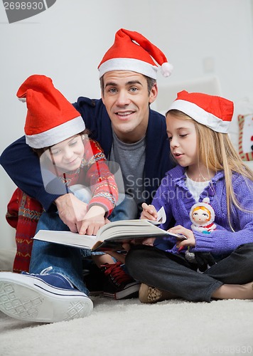 Image of Father With Children Reading Book During Christmas