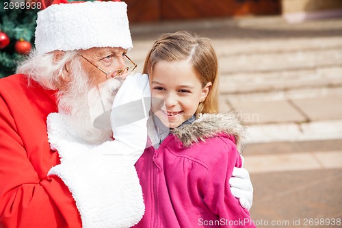 Image of Santa Claus Whispering In Girl's Ear