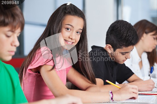 Image of Teenage Girl Sitting With Classmates Studying At Desk