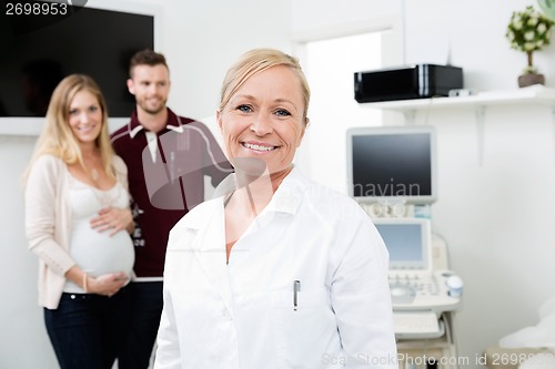 Image of Happy Doctor With Expectant Couple In Background