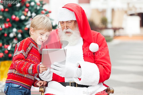 Image of Boy And Santa Claus Using Digital Tablet