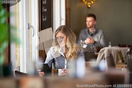 Image of Woman Using Digital Tablet With Man In Background