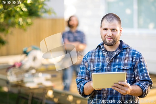 Image of Manual Worker Holding Digital Tablet With Coworker Standing In B