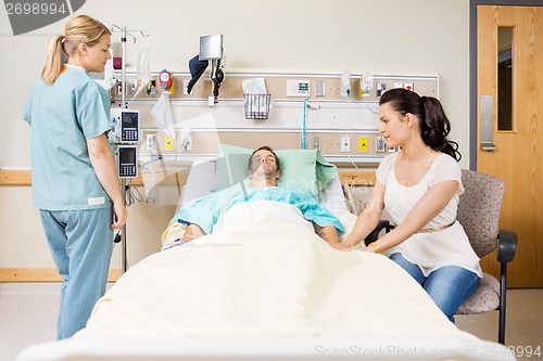 Image of Woman Holding Patient's Hand In Hospital Room