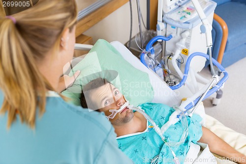 Image of Patient Looking At Nurse As She Adjusts His Pillow