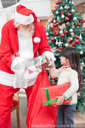 Image of Santa Claus Giving Gifts To Girl