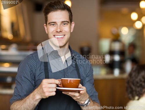 Image of Happy Waiter Holding Coffee Cup In Cafeteria