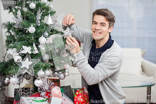 Image of Man Smiling While Decorating Christmas Tree