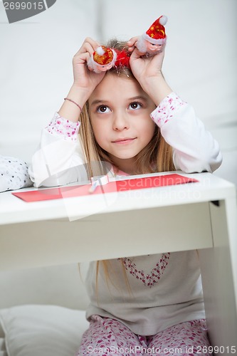 Image of Thoughtful Girl Holding Santa Headband